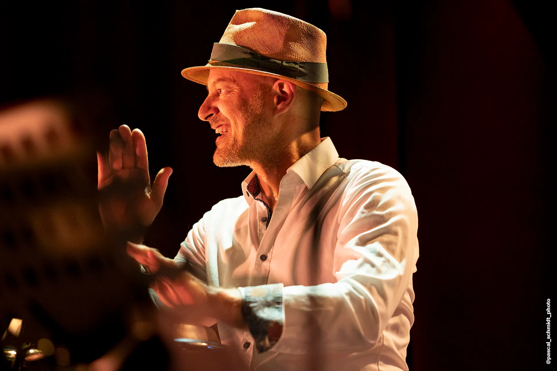 Laurent Cuénoud aux congas, chapeau panama, dans la lumière ambrée du club Les Jumeaux