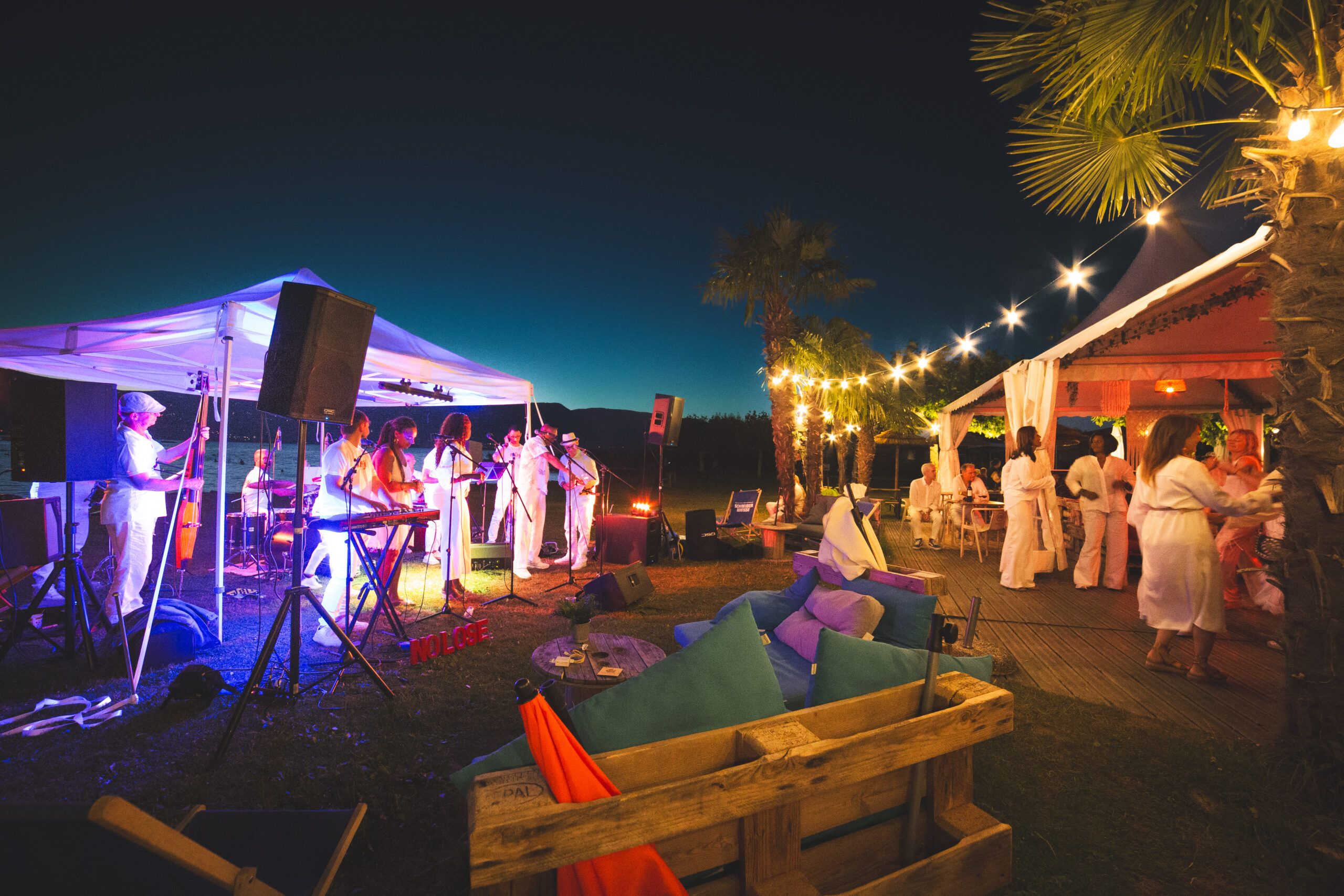 Invités dansant devant Nolosé Salsa lors d'une fête privée à Estavayer, guirlandes au-dessus de la piste