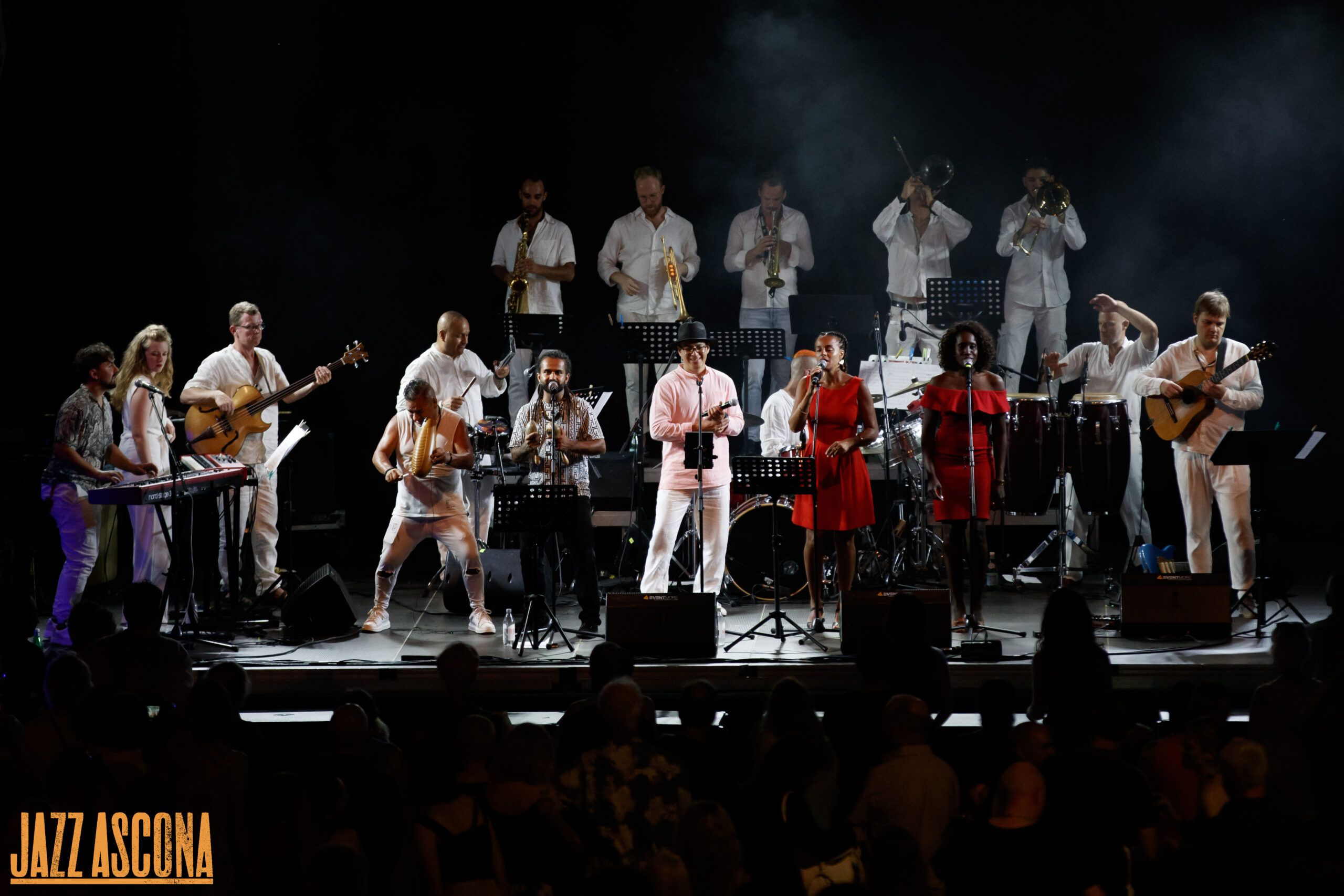 Nolosé Salsa au complet sur la grande scène de JazzAscona — seize musiciens en blanc, les chanteuses en rouge